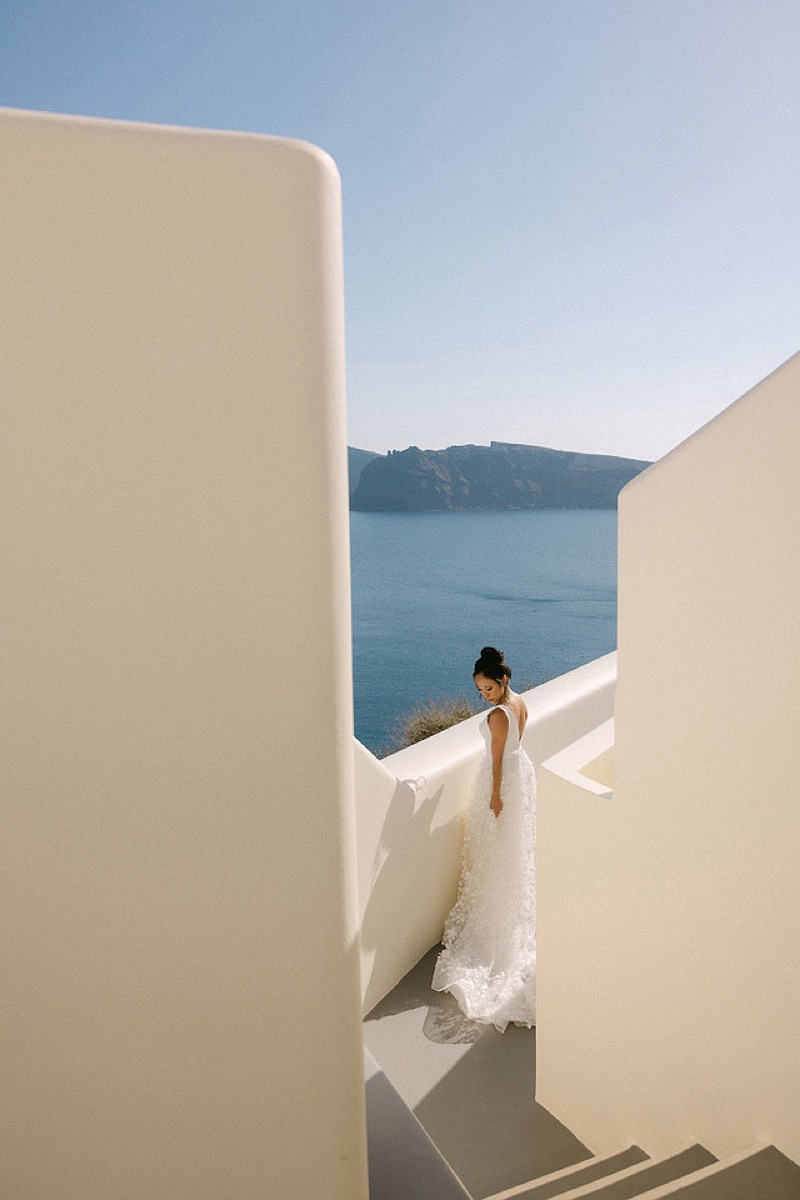 A bride between whitewashed walls above the Santorini caldera